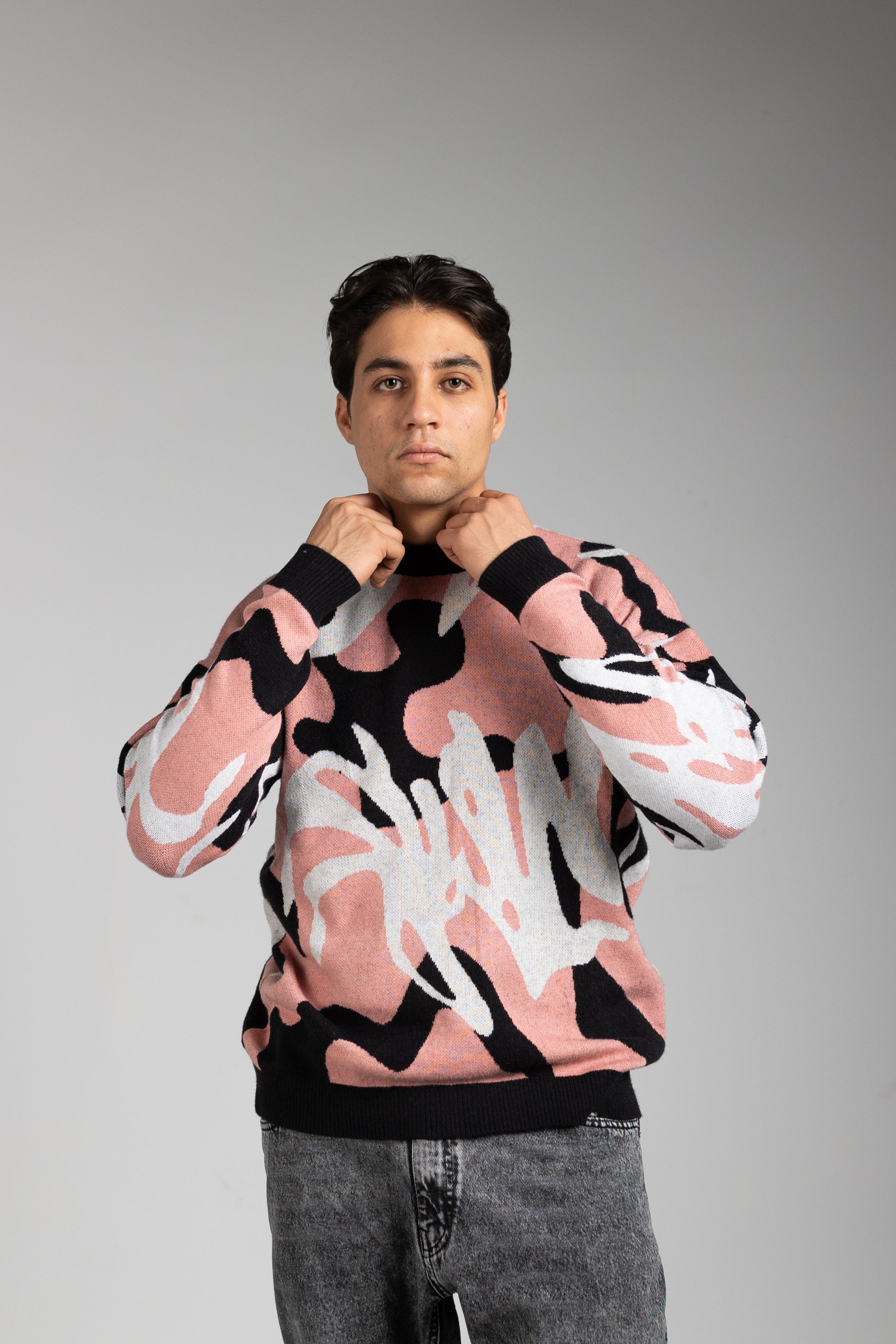 Person wearing a colorful sweater with abstract design on a gray background
